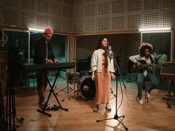A band recording together in a studio with keys, vocals and guitar